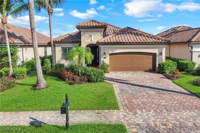 mediterranean / spanish-style house with an attached garage, a tiled roof, decorative driveway, stucco siding, and a front lawn