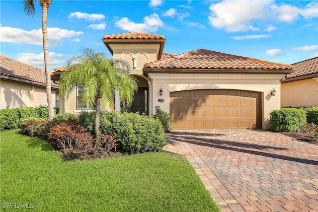 mediterranean / spanish house with a front lawn, decorative driveway, an attached garage, and stucco siding