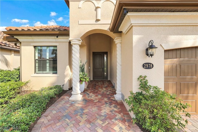 property entrance with a garage, a tiled roof, and stucco siding