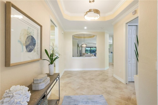 hall featuring ornamental molding, a raised ceiling, and baseboards