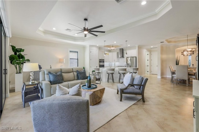 living room featuring recessed lighting, ornamental molding, a raised ceiling, and ceiling fan with notable chandelier