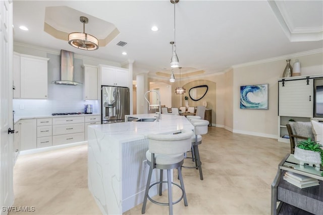 kitchen featuring visible vents, stainless steel fridge with ice dispenser, ornamental molding, wall chimney range hood, and a sink