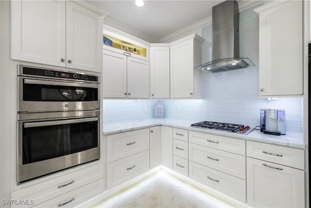 kitchen featuring white cabinets, appliances with stainless steel finishes, decorative backsplash, light stone countertops, and wall chimney exhaust hood