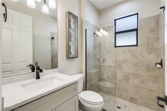 bathroom with tiled shower, vanity, and toilet