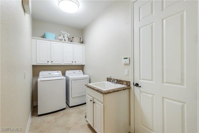 clothes washing area with cabinet space, independent washer and dryer, and a sink