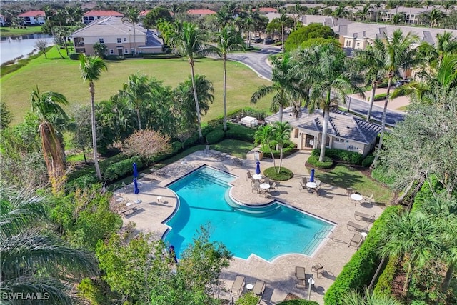 community pool featuring a patio, a yard, a water view, and a residential view