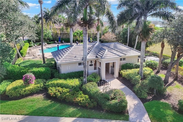 view of front of home with a tiled roof, a patio area, a community pool, and stucco siding