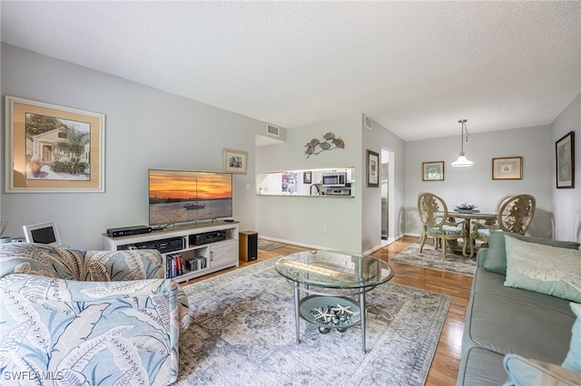 living room featuring a textured ceiling and light wood-type flooring