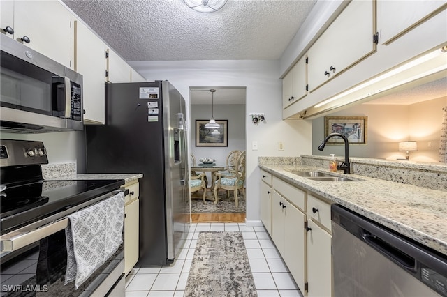 kitchen featuring sink, hanging light fixtures, light tile patterned floors, stainless steel appliances, and white cabinets