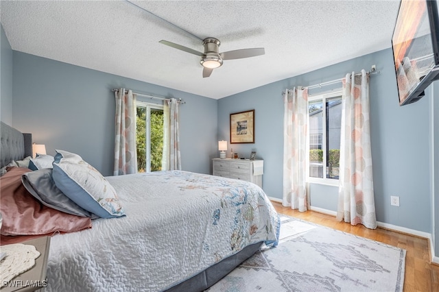 bedroom with hardwood / wood-style floors, a textured ceiling, and ceiling fan