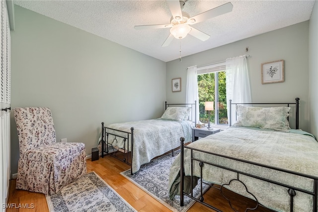 bedroom with ceiling fan, hardwood / wood-style flooring, and a textured ceiling