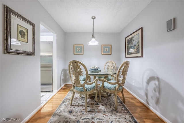 dining area featuring light hardwood / wood-style flooring and a textured ceiling