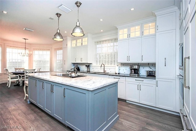 kitchen featuring a center island with sink, hanging light fixtures, and white cabinets