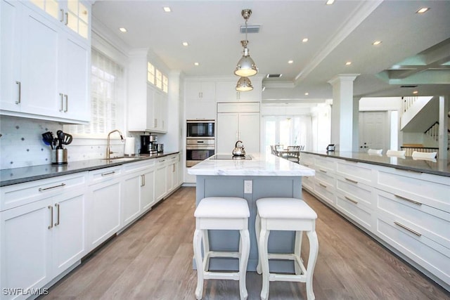 kitchen with black appliances, a kitchen breakfast bar, a kitchen island, pendant lighting, and white cabinets