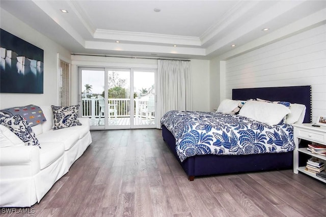 bedroom with hardwood / wood-style flooring, access to outside, and a raised ceiling