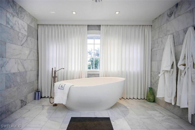 bathroom with a bathtub and tile walls