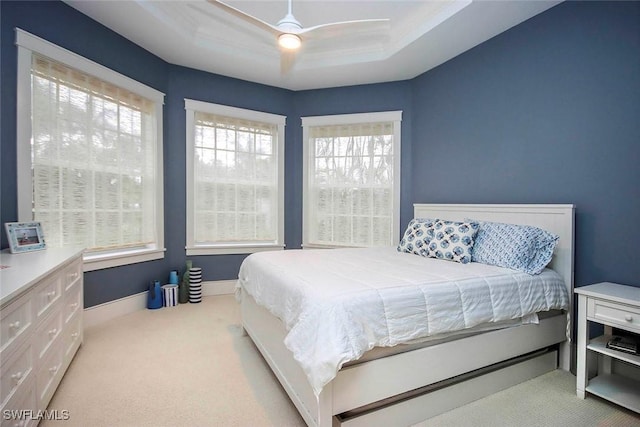 carpeted bedroom featuring a raised ceiling and ceiling fan