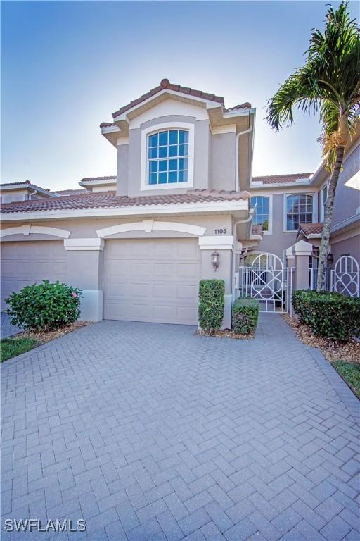 view of front of property with a garage, decorative driveway, a tiled roof, and stucco siding