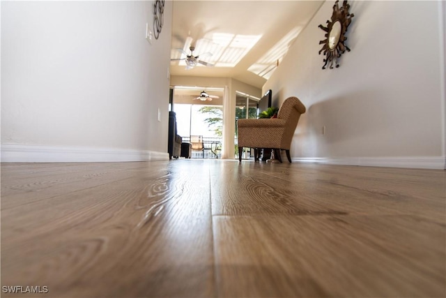 interior space featuring a ceiling fan, baseboards, and wood finished floors