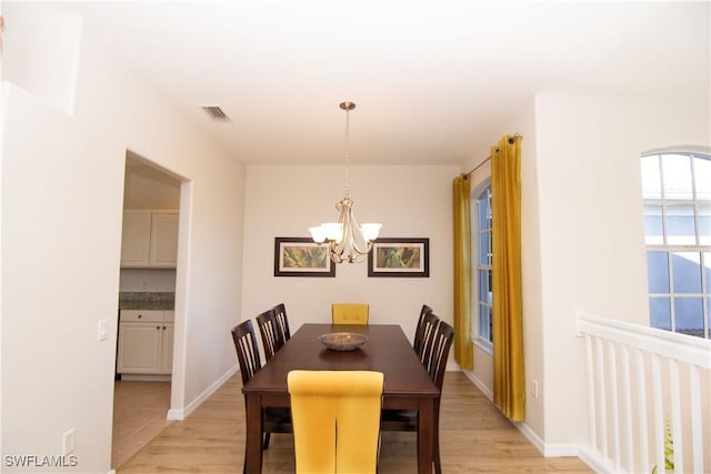 dining space featuring baseboards, light wood finished floors, visible vents, and an inviting chandelier