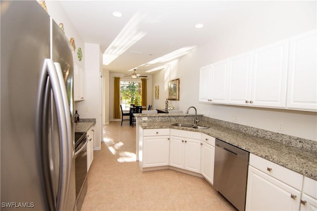 kitchen featuring appliances with stainless steel finishes, white cabinets, a sink, and light stone countertops