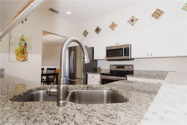 kitchen featuring light stone counters, white cabinets, and appliances with stainless steel finishes