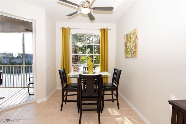 dining space featuring light tile patterned floors, ceiling fan, and a water view