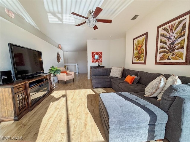 living room with light wood finished floors, ceiling fan, and visible vents