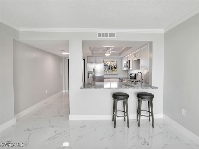 kitchen featuring appliances with stainless steel finishes, sink, white cabinetry, crown molding, and kitchen peninsula