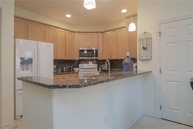 kitchen featuring dark stone countertops, hanging light fixtures, white appliances, and kitchen peninsula