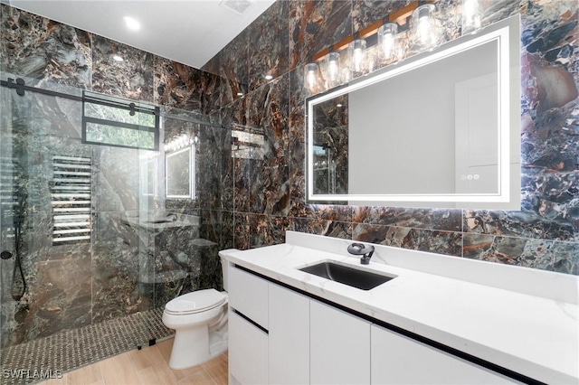 bathroom featuring vanity, toilet, tile walls, and a tile shower