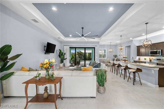 142 SW 35th Ave, Cape Coral, FL 33991 - living room with ornamental molding, a tray ceiling, and ceiling fan with notable chandelier