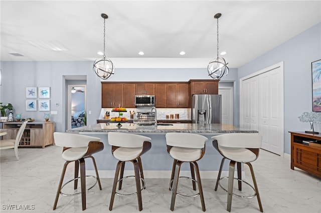 142 SW 35th Ave, Cape Coral, FL 33991 - kitchen with appliances with stainless steel finishes, sink, dark stone counters, hanging light fixtures, and a center island with sink