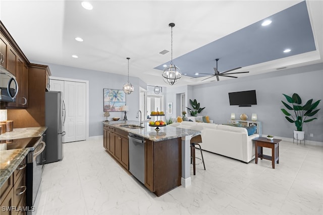 142 SW 35th Ave, Cape Coral, FL 33991 - kitchen featuring appliances with stainless steel finishes, sink, hanging light fixtures, a kitchen island with sink, and a tray ceiling
