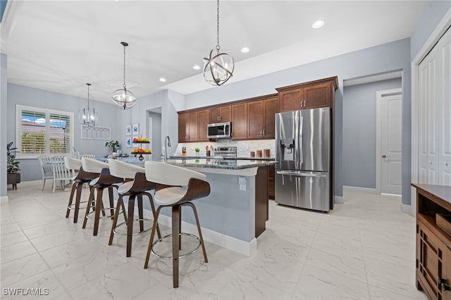 142 SW 35th Ave, Cape Coral, FL 33991 - kitchen featuring a breakfast bar, appliances with stainless steel finishes, an inviting chandelier, hanging light fixtures, and a center island with sink