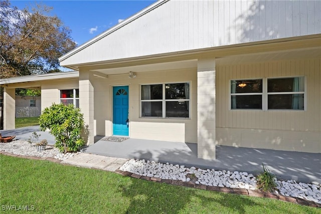 view of exterior entry featuring a yard and covered porch