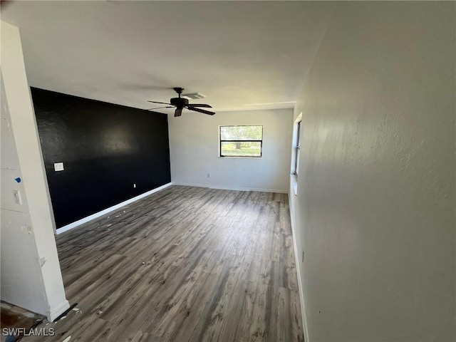 spare room featuring baseboards, dark wood finished floors, and a ceiling fan