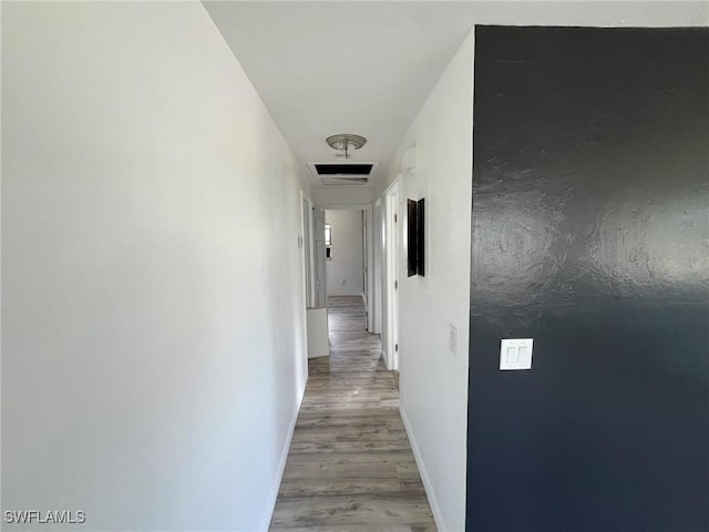 hallway with wood finished floors, visible vents, and baseboards