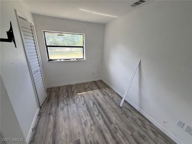 unfurnished bedroom with a closet, visible vents, baseboards, and wood finished floors