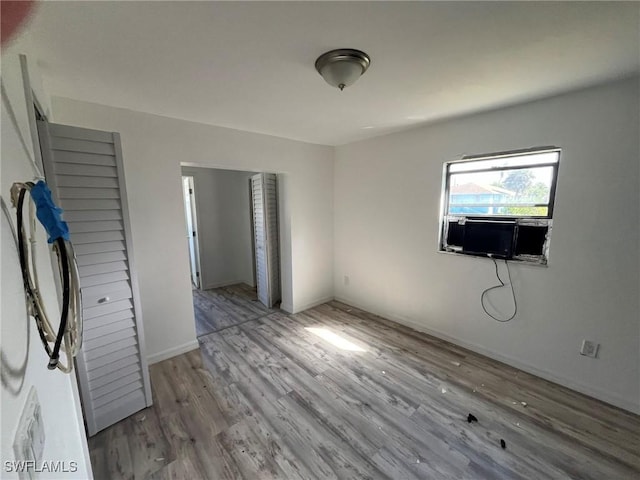 unfurnished bedroom featuring cooling unit and wood finished floors