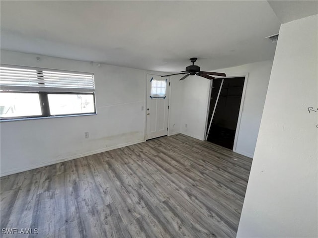 empty room featuring light wood finished floors, visible vents, a ceiling fan, and a wealth of natural light