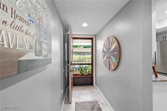 doorway to outside with marble finish floor, baseboards, and a textured ceiling