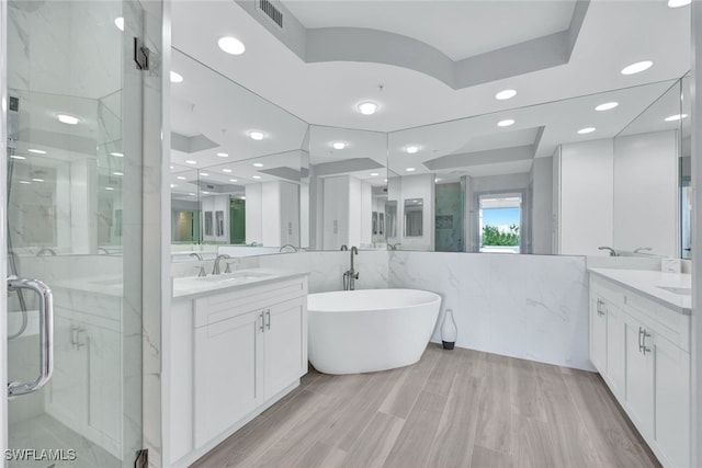 bathroom with hardwood / wood-style flooring, vanity, separate shower and tub, and tile walls