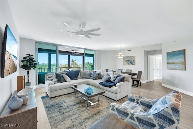 living room with hardwood / wood-style flooring, ceiling fan with notable chandelier, and floor to ceiling windows