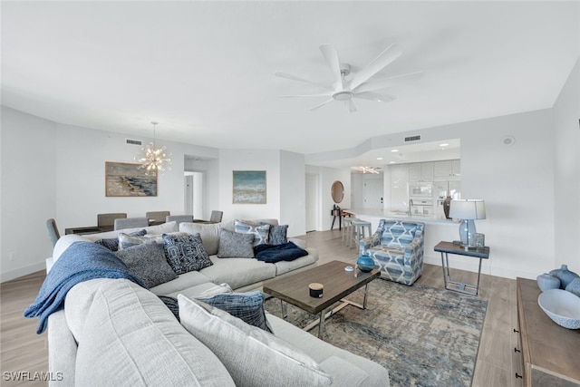 living room featuring sink, ceiling fan with notable chandelier, and light hardwood / wood-style flooring