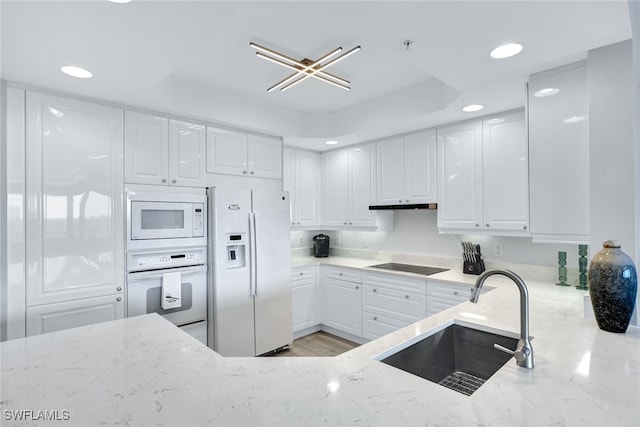 kitchen featuring white cabinetry, light stone countertops, sink, and white appliances