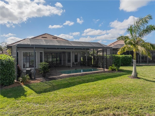 back of property with a fenced in pool, glass enclosure, and a lawn