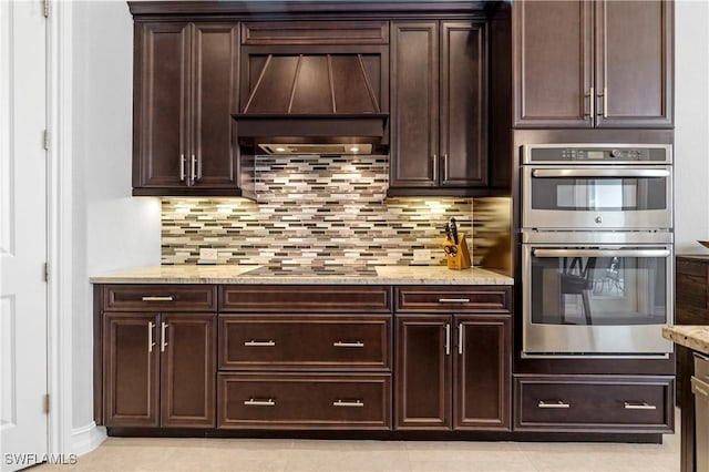 kitchen featuring decorative backsplash, custom exhaust hood, black electric stovetop, light stone counters, and stainless steel double oven