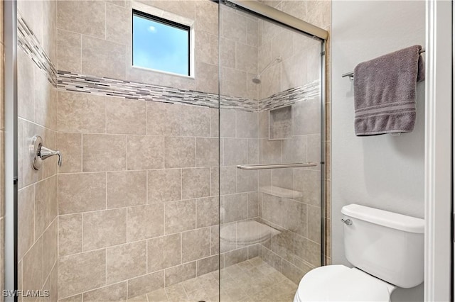 bathroom featuring a shower with door and toilet