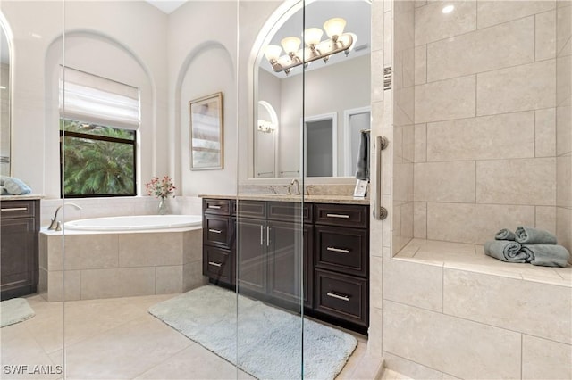 bathroom featuring tile patterned floors, vanity, and tiled bath